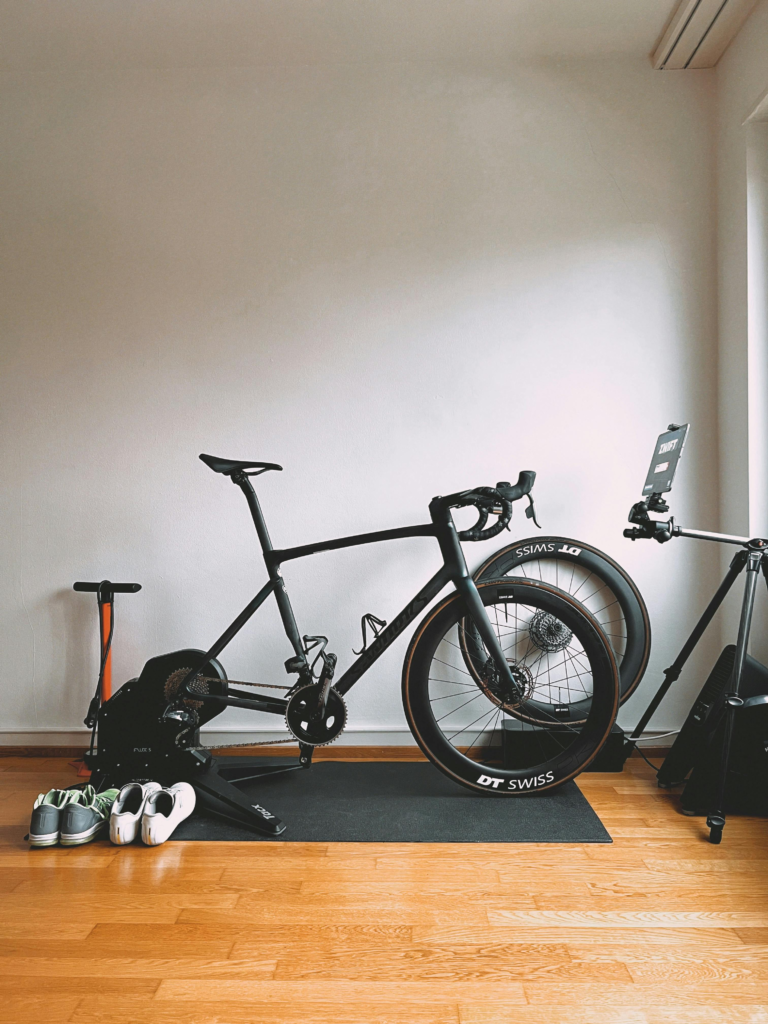 Minimalist indoor cycling setup featuring a sleek road bike and sports equipment for virtual training.